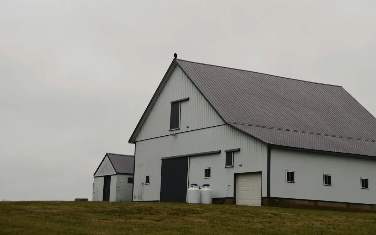 White metal-sided pole barn with sliding and overhead doors