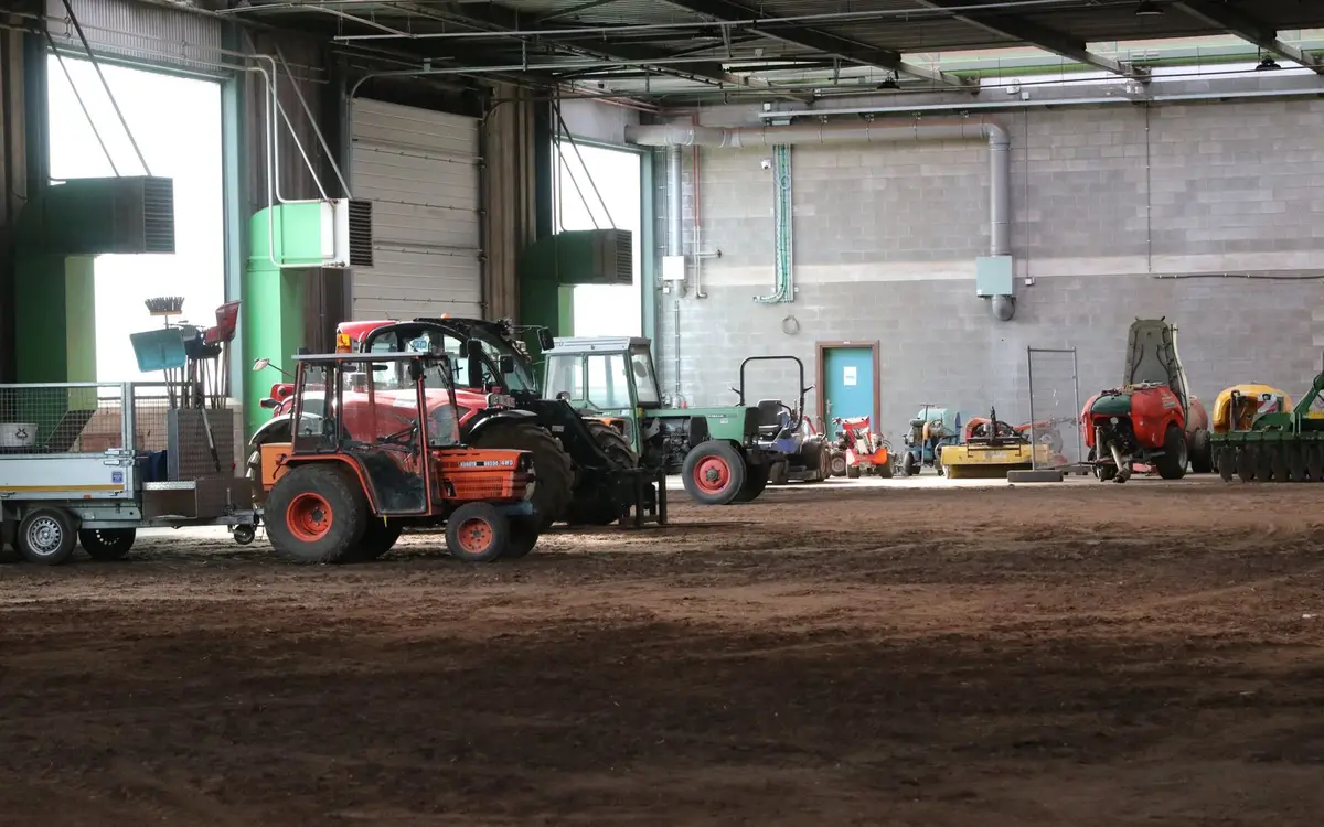 Tractors and farm equipment parked inside a large farm building