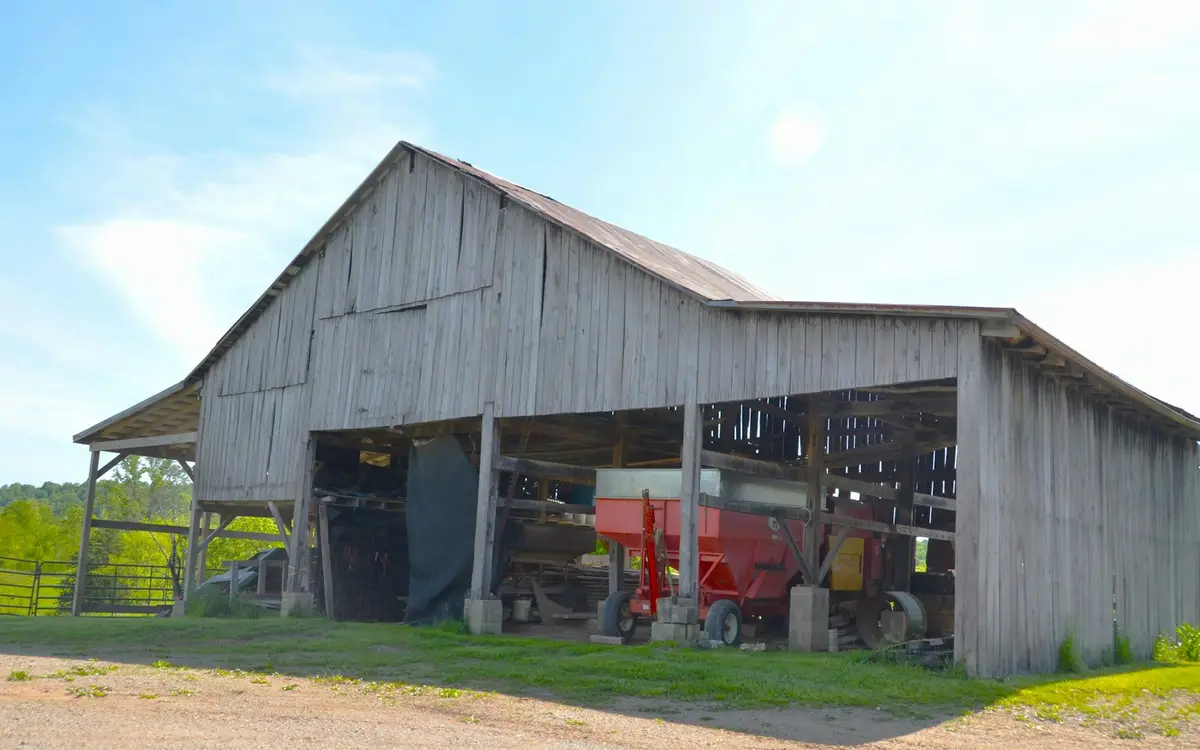 Open-front machine shed sheltering a grain trailer