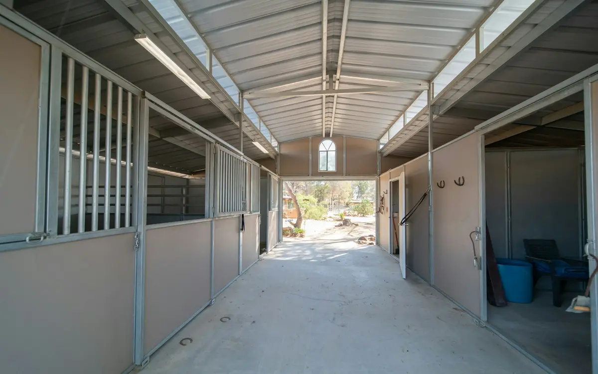 Center aisle of a steel-framed horse barn lined with stalls
