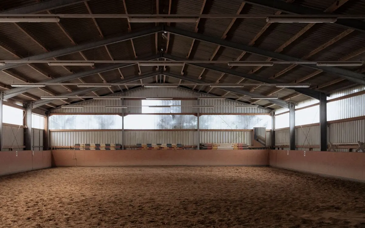 Empty indoor riding arena under a steel roof