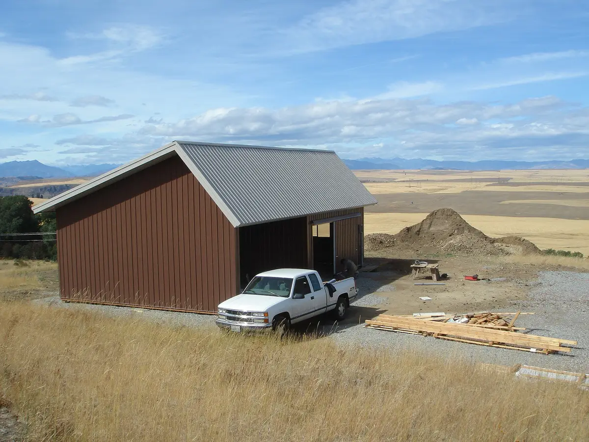 Brown pole barn garage with a metal roof and open bay